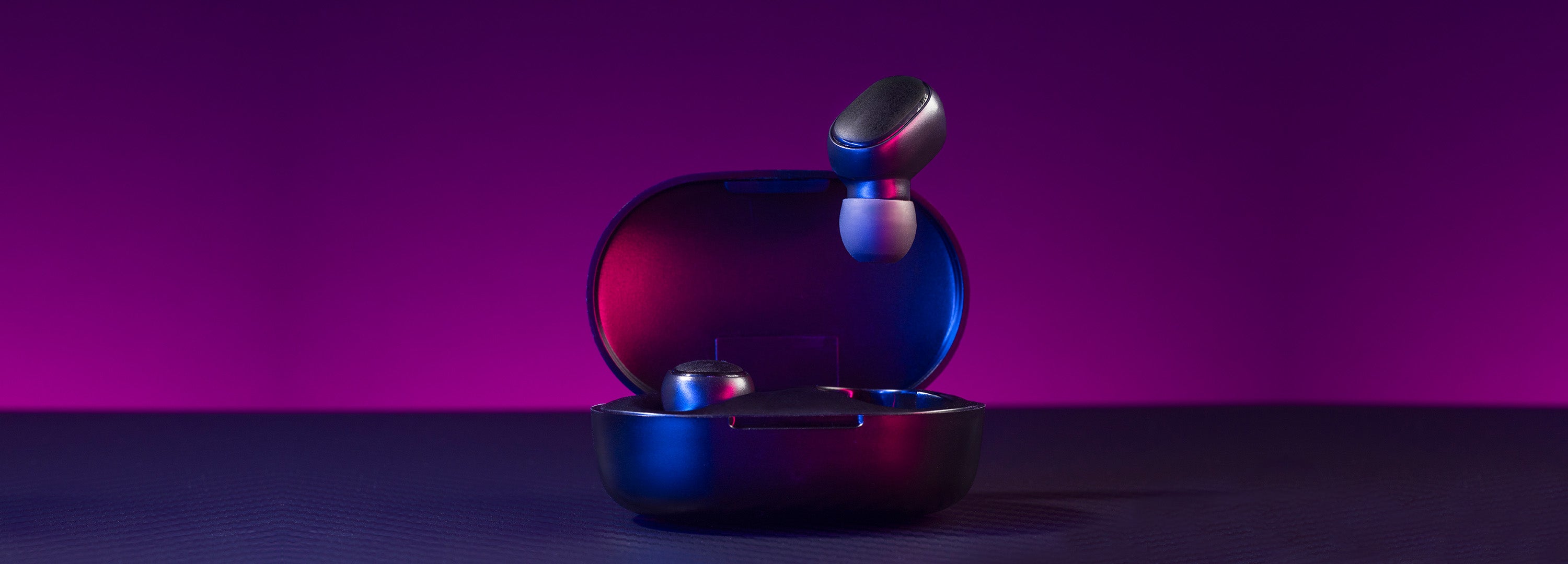 Blue and red electronic device on a dark surface with a purple background